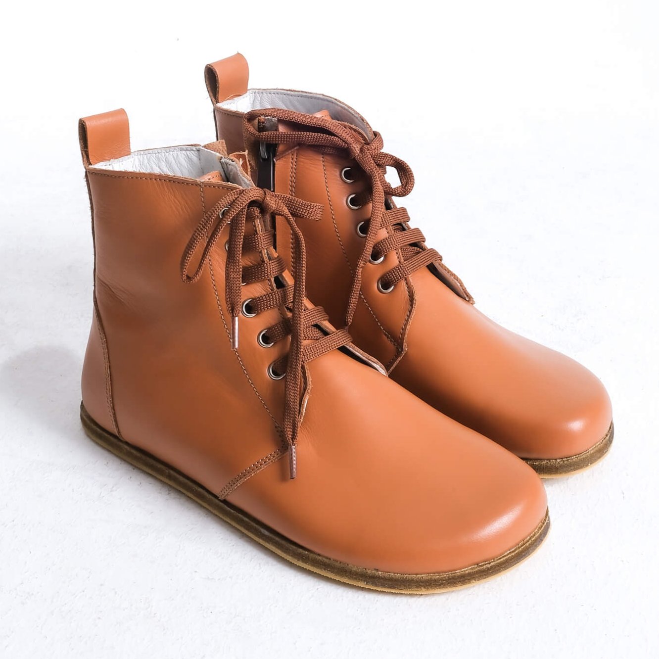 Stylish tan brown barefoot ankle boots with a sleek design and lace-up front, perfect for modern casual wear.