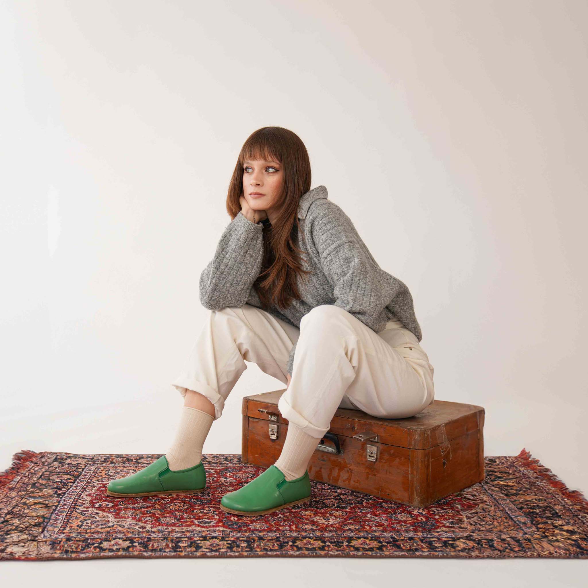 Model wearing green leather loafers from Pelanir - stylish barefoot shoes for women. Natural fit and comfort.
