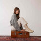 Model sitting on a suitcase wearing Ionia beige loafers - Elevate your style with Ionia Leather Barefoot Women Loafers in beige.