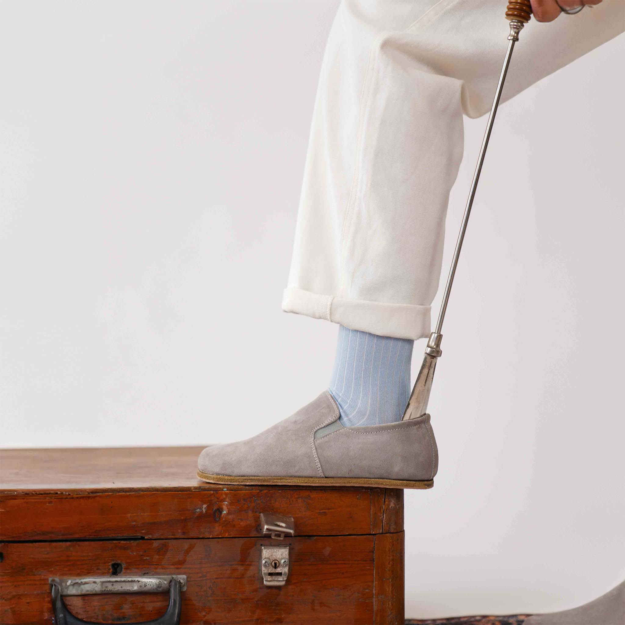 Gray suede loafers worn with light blue socks, side view showcasing their natural foot positioning.