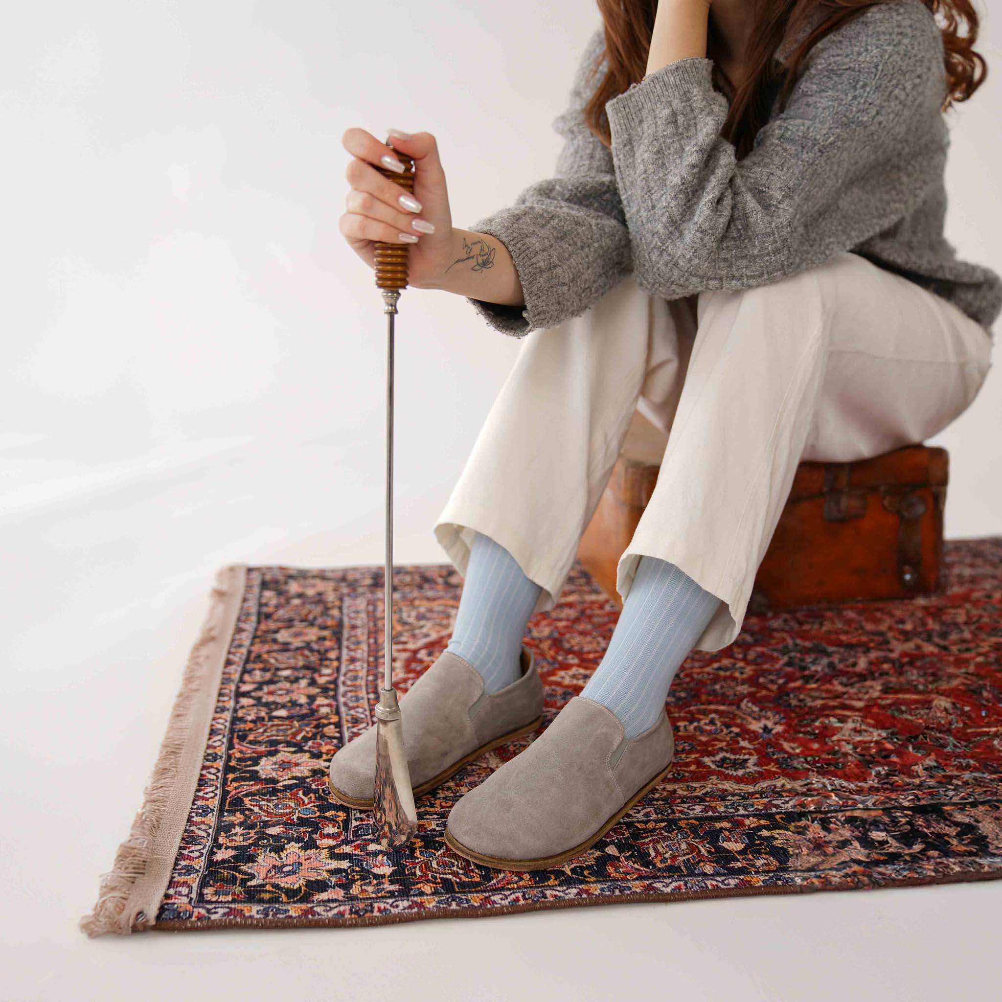 Close-up of gray suede loafers worn by a model on a Turkish rug, highlighting their minimalist elegance.