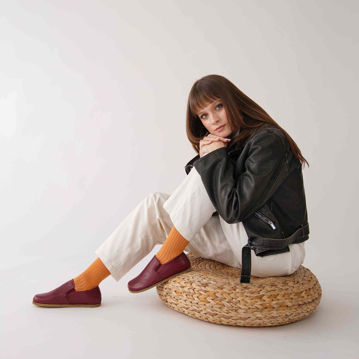 Model showcasing Burgundy loafers paired with white trousers and orange socks.