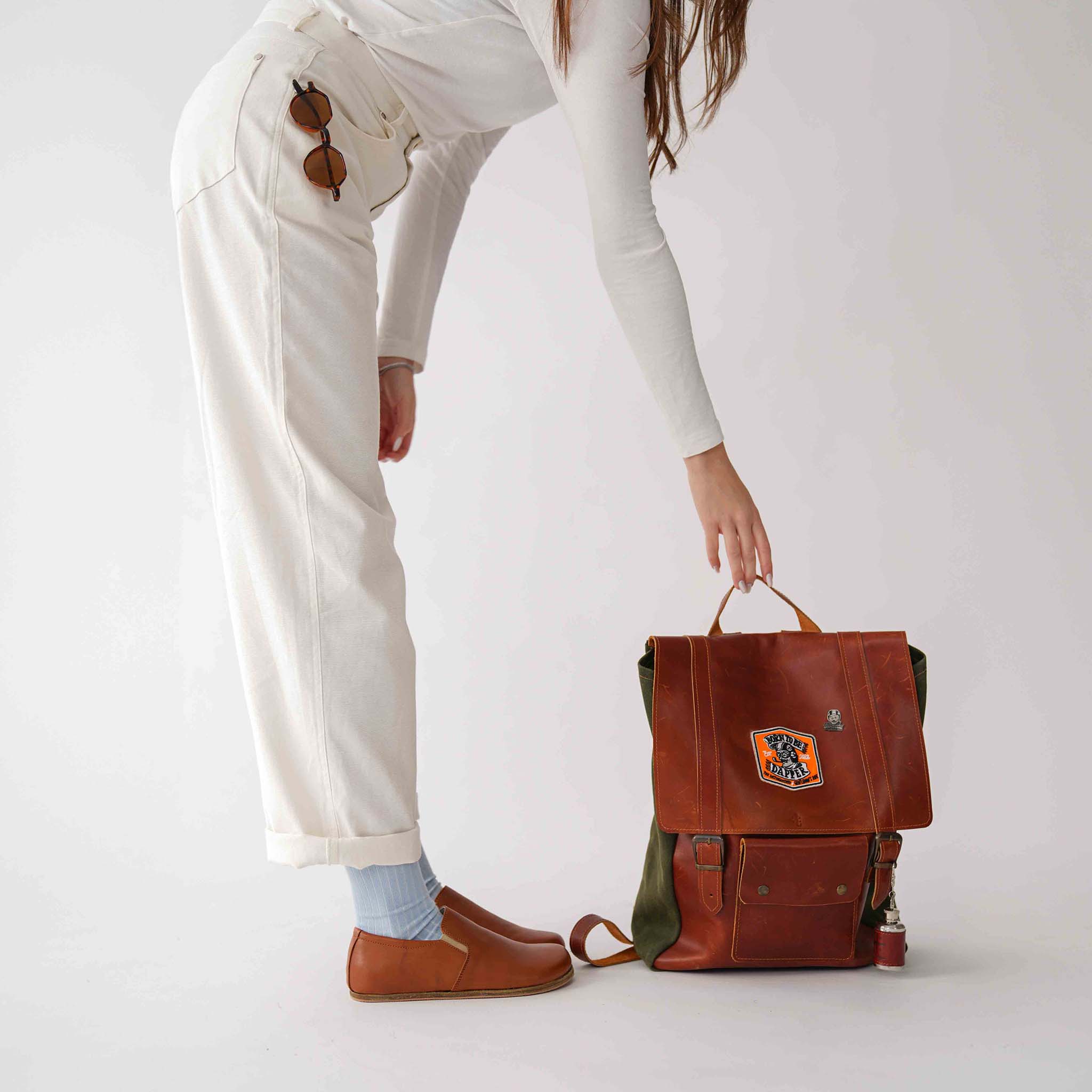 Model in tan brown Ionia leather barefoot loafers, paired with a white outfit and sunglasses, adding a touch of elegance.