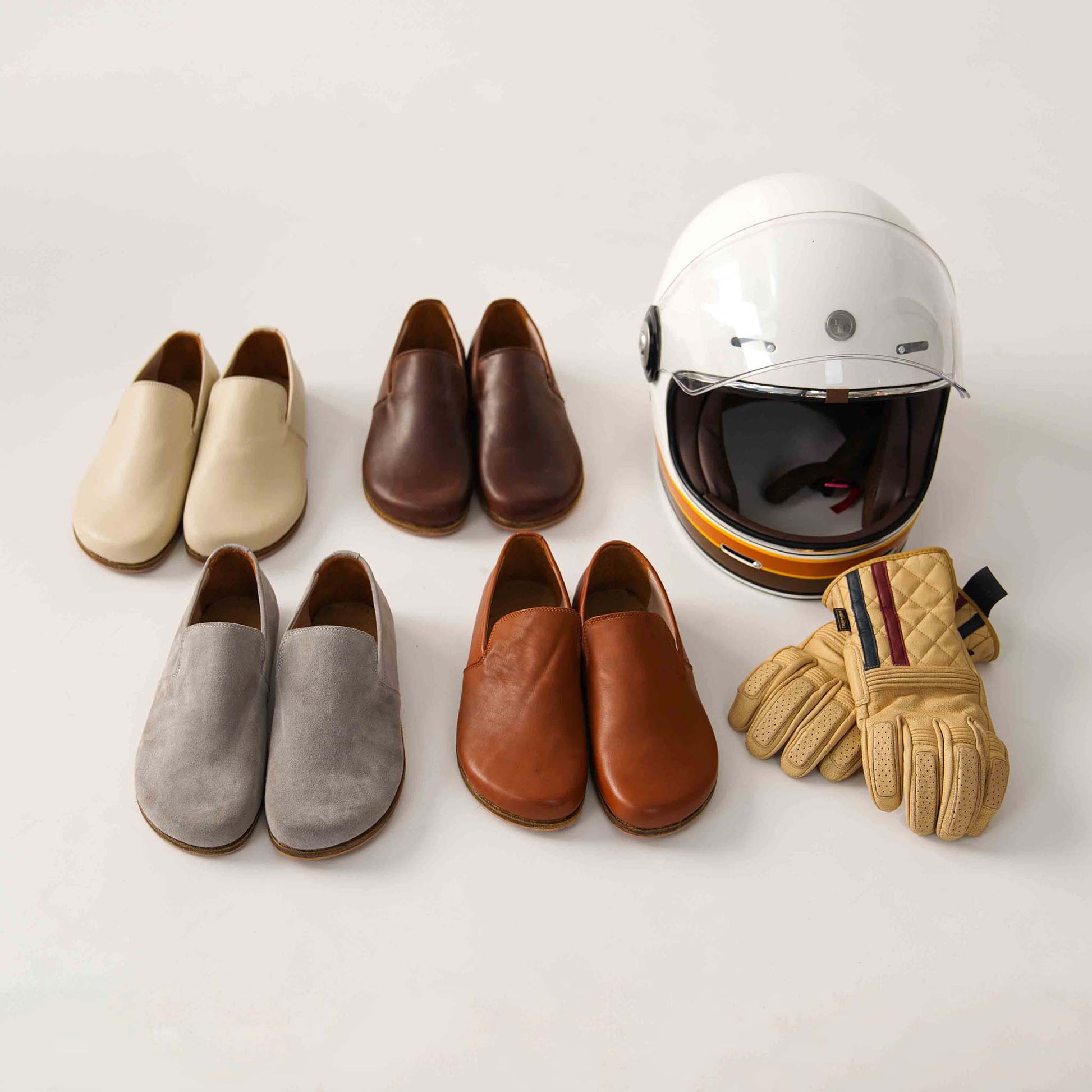 Collection of Aeolia leather barefoot loafers in various colors, displayed with a helmet and gloves.