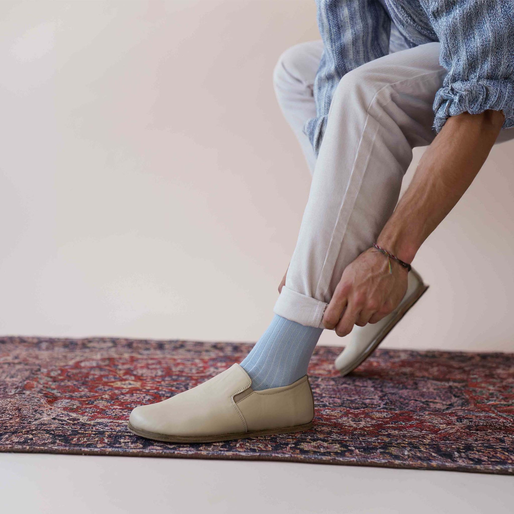 Model adjusting pants while wearing Ionia Leather Barefoot Men Loafers in beige, emphasizing the casual and comfortable fit.