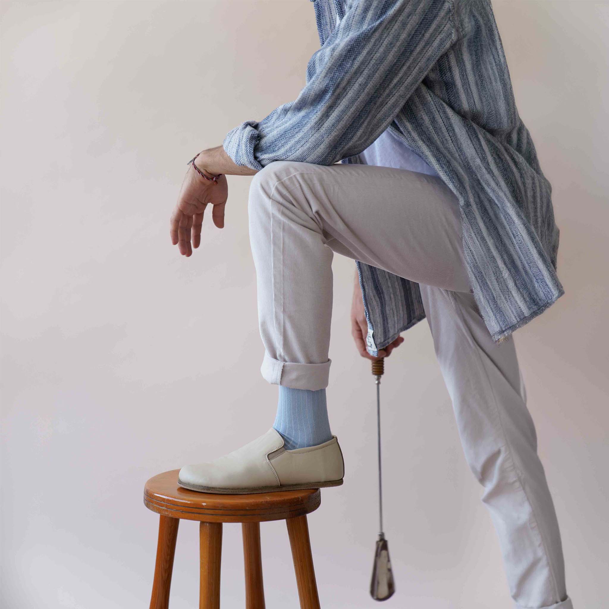 Flexible Ionia Leather Barefoot Men Loafers in beige held by a model, demonstrating the soft and flexible leather material.