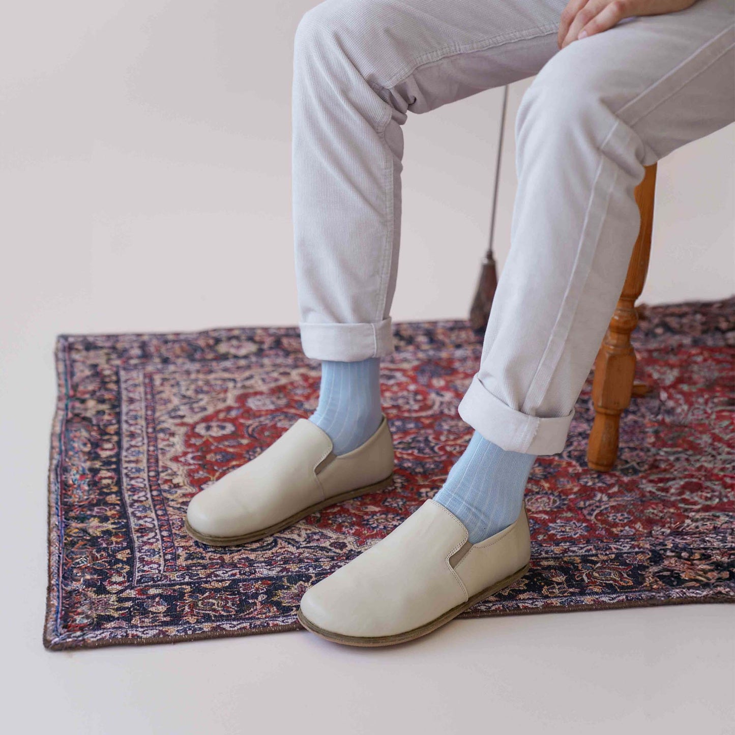 Ionia Leather Barefoot Men Loafers in beige on a patterned rug, showcasing the natural fit and minimalist design.