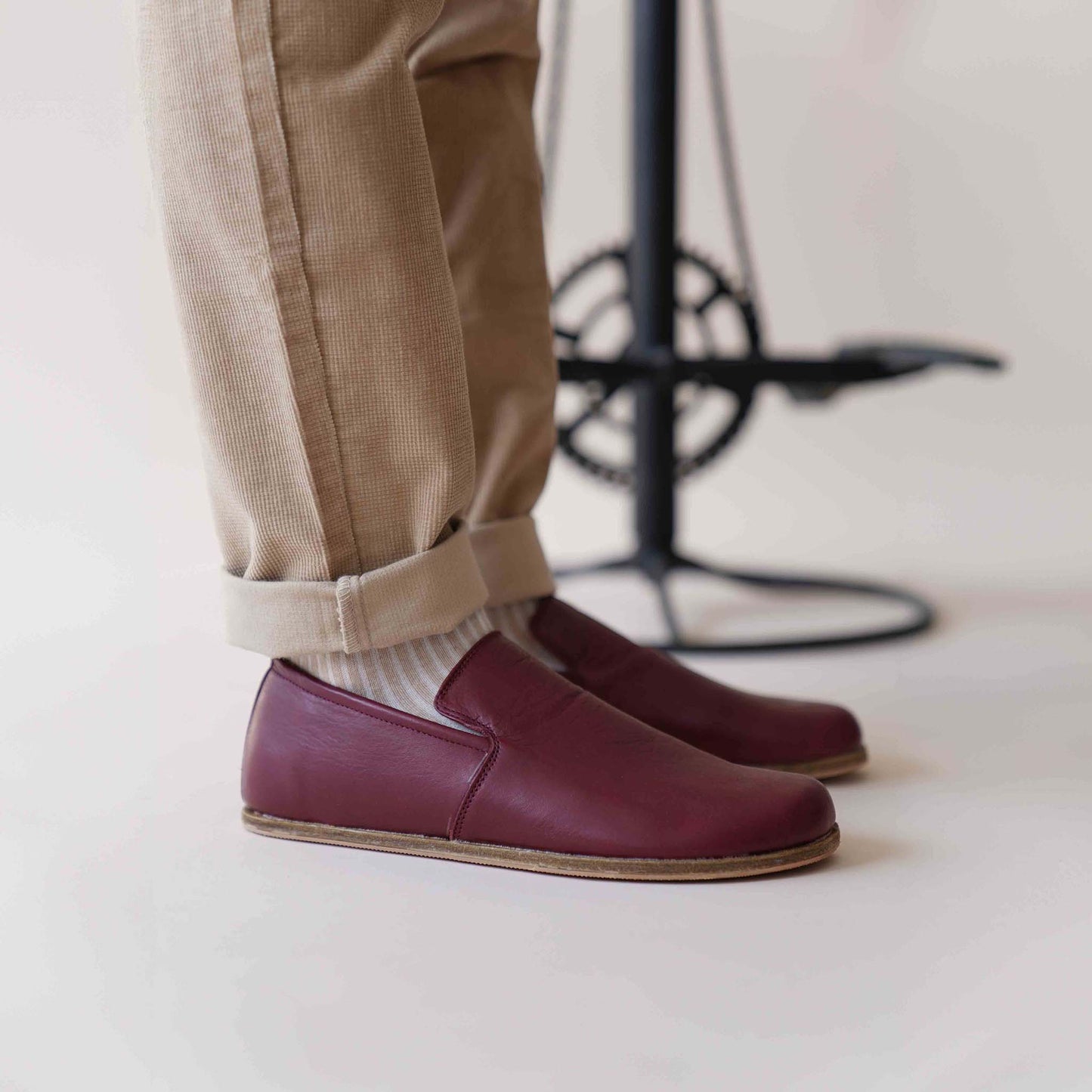 Burgundy Aeolia leather barefoot men's loafers paired with rolled-up beige pants and white socks. Get these versatile loafers at pelanir.com!