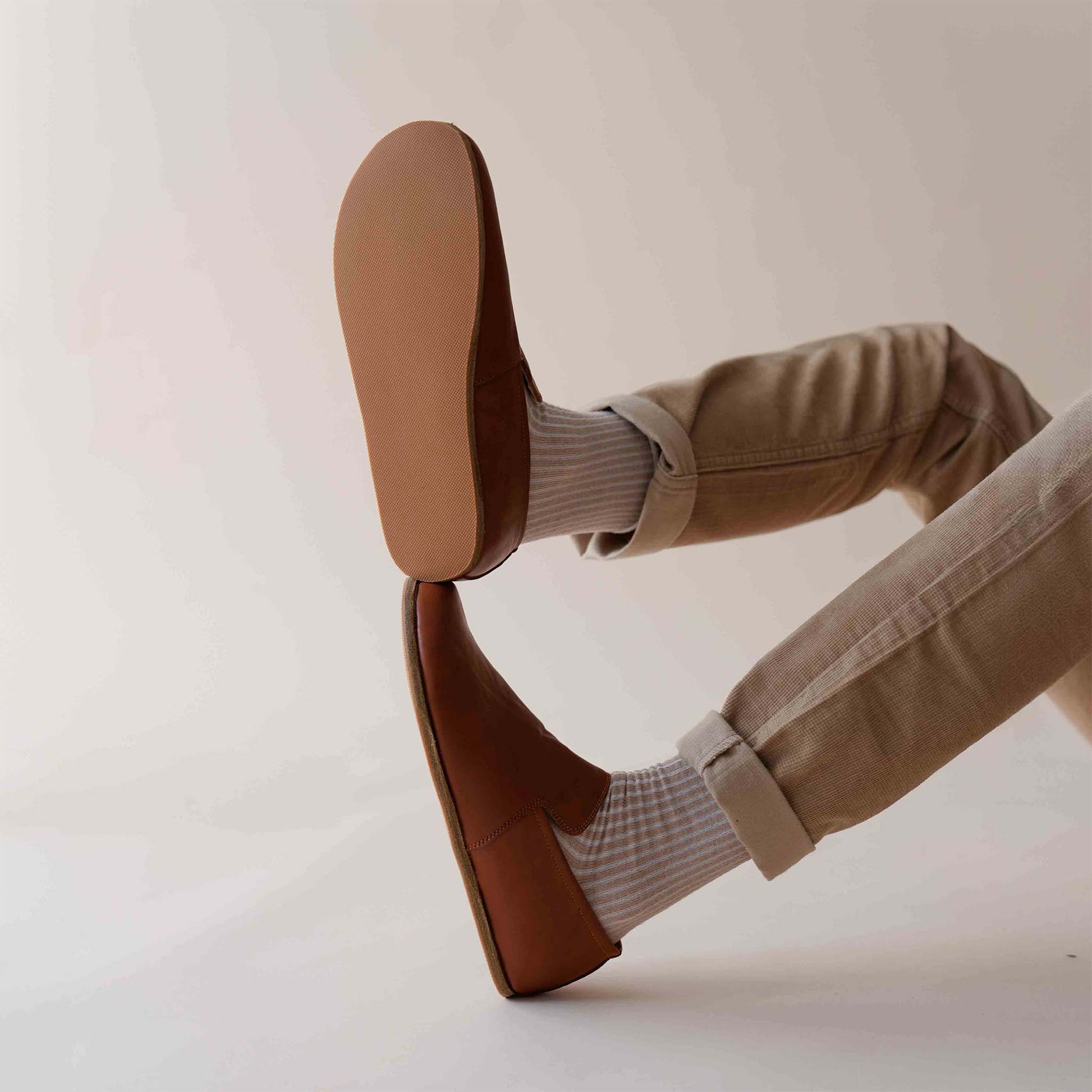 Relaxed style with Tan brown Aeolia Leather Barefoot Men's Loafers, paired with beige pants and white socks, highlighting the flexible sole.