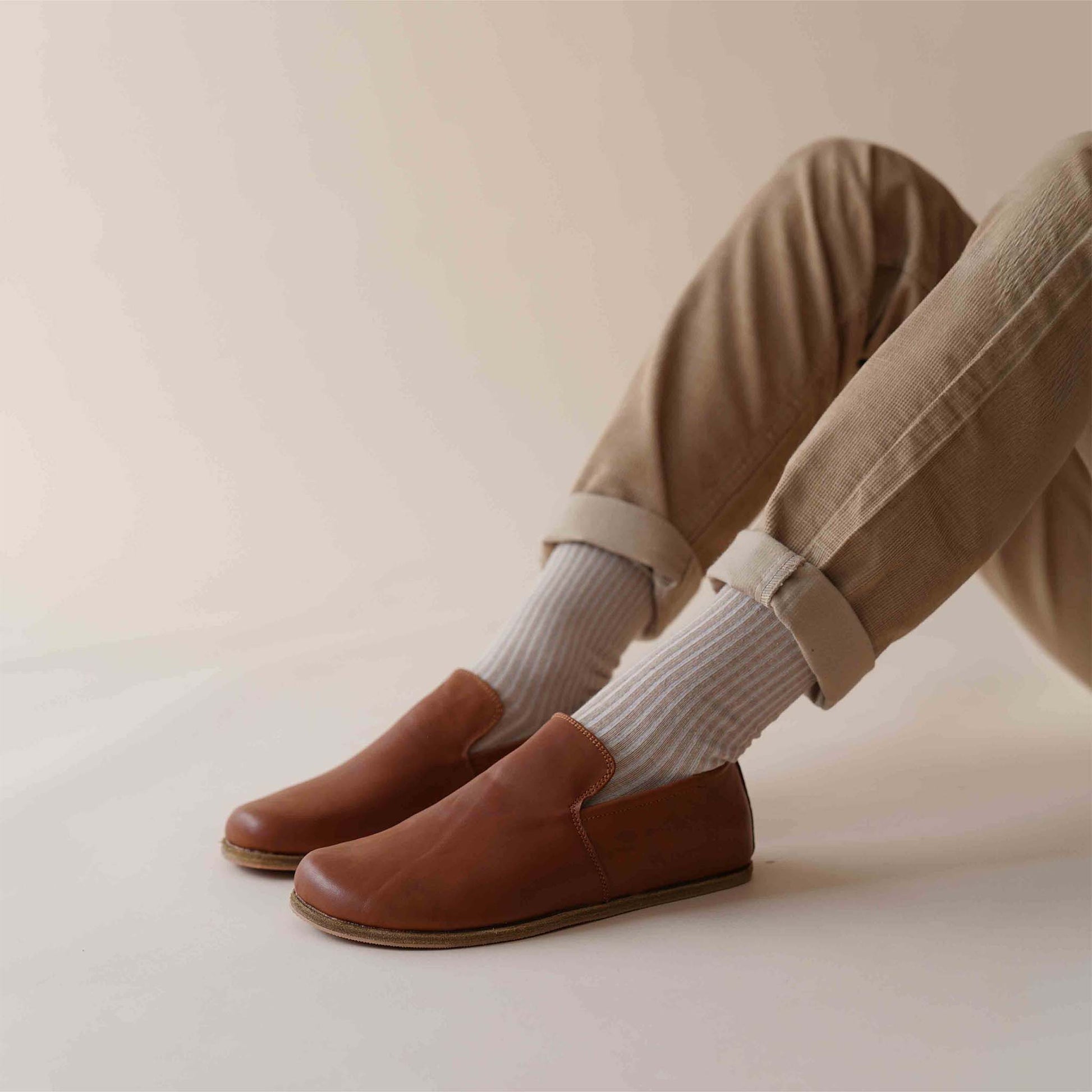 Casual look with Tan brown Aeolia Leather Barefoot Men's Loafers, paired with beige pants and white socks for a relaxed and stylish outfit.