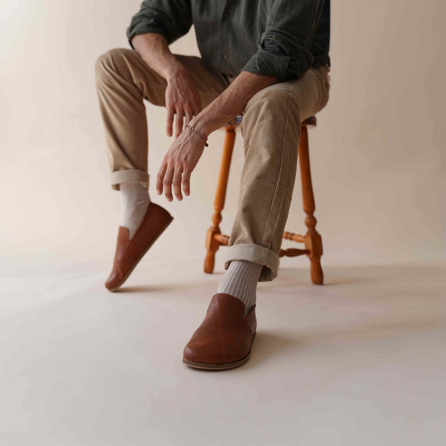 Casual look with Tan brown Aeolia Leather Barefoot Men's Loafers, paired with beige pants and white socks, highlighting a relaxed style.