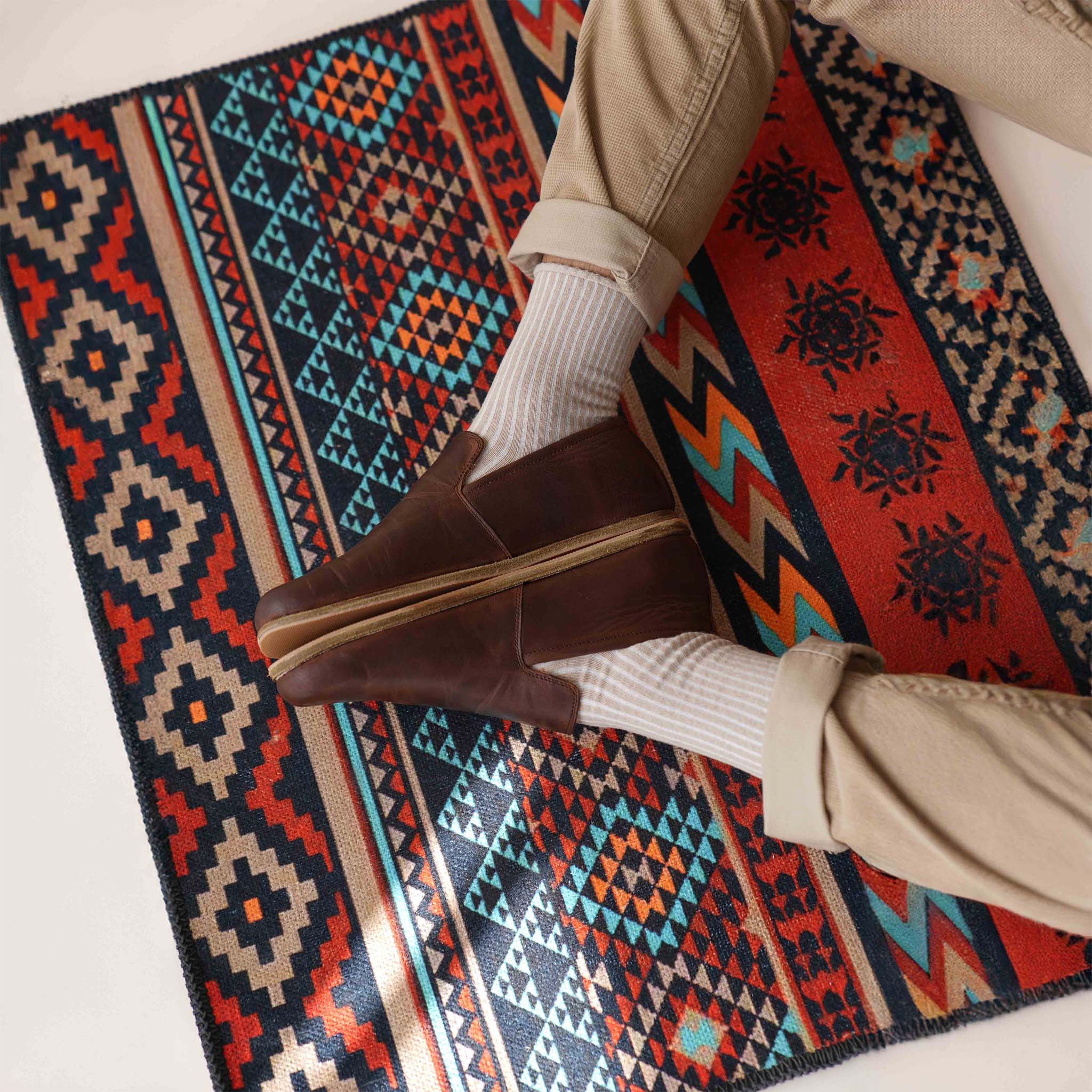 Aeolia brown leather barefoot men loafers styled with beige pants and colorful rug, emphasizing comfort and flexibility. Visit pelanir.com!