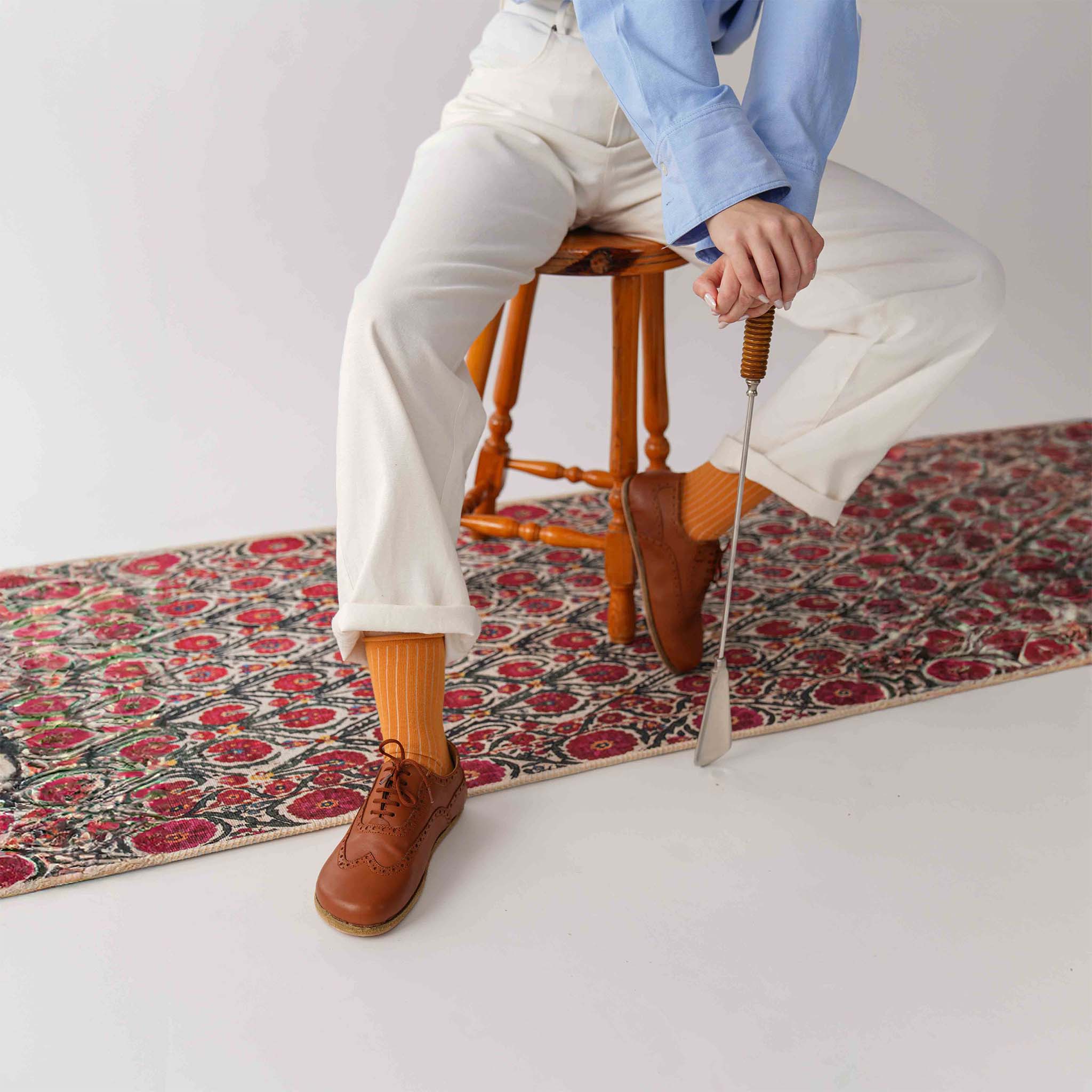 Model demonstrating the flexibility and style of tan brown Doris leather barefoot women Oxfords while seated on a patterned rug.