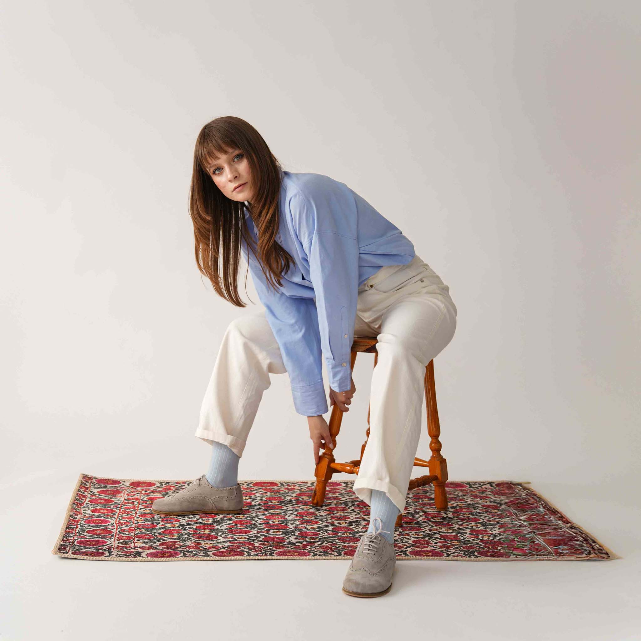Model wearing gray Doris leather barefoot women's oxfords, bending forward, showcasing the comfortable and stylish look.