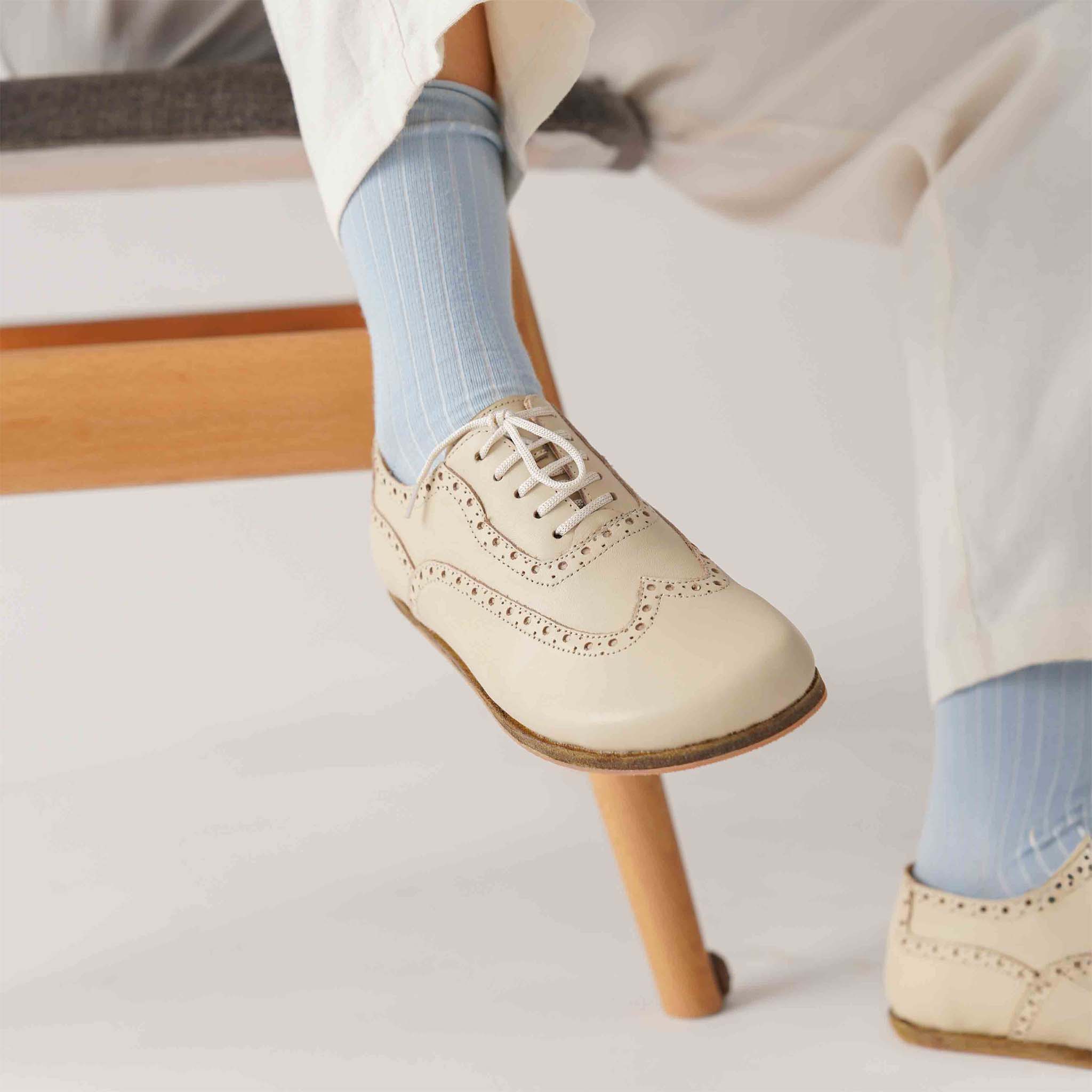 Side view of a woman's feet in beige Doris leather barefoot women's oxfords, demonstrating their stylish and natural design.