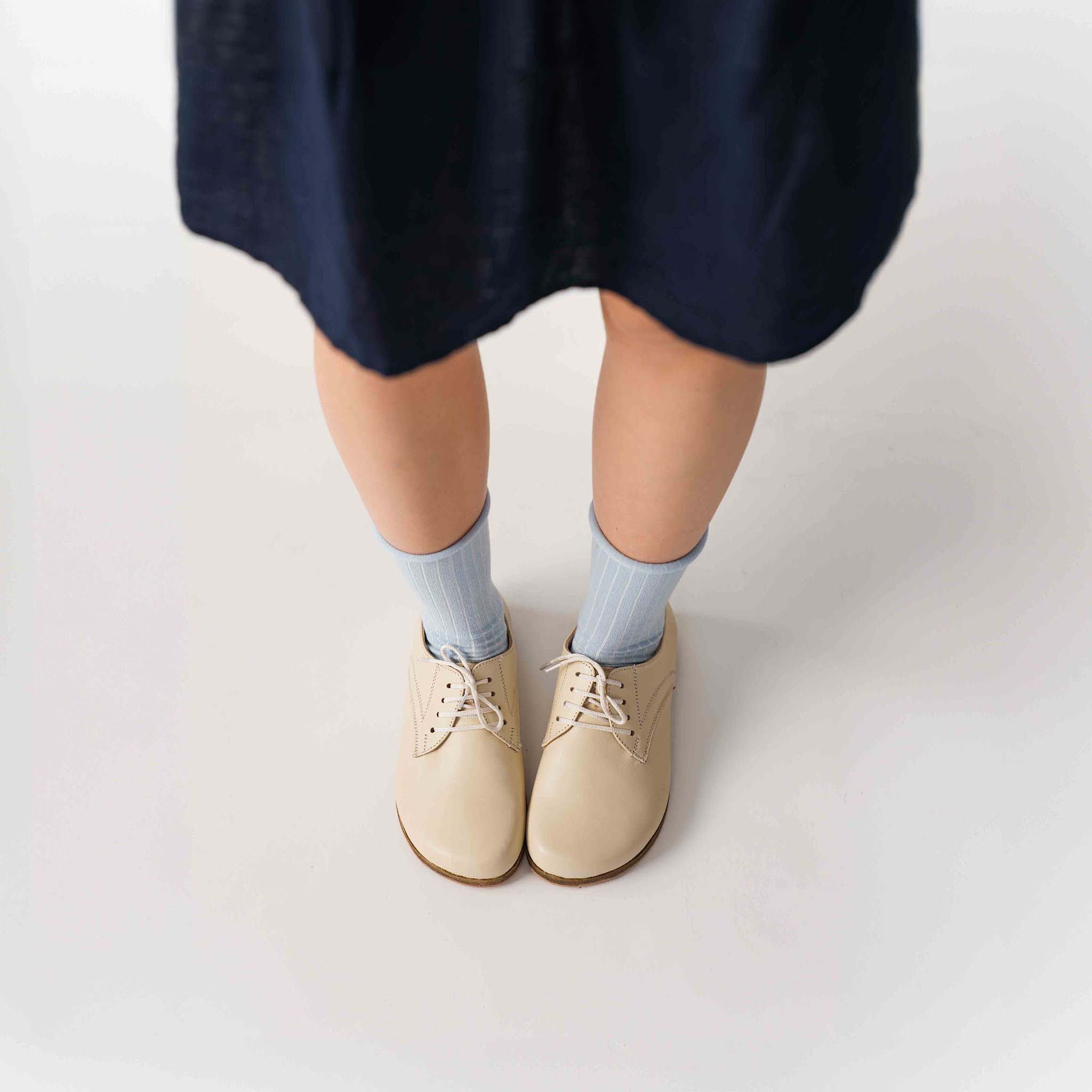 Locris beige leather barefoot women's oxfords worn with a navy dress, showcasing versatility and chic design.