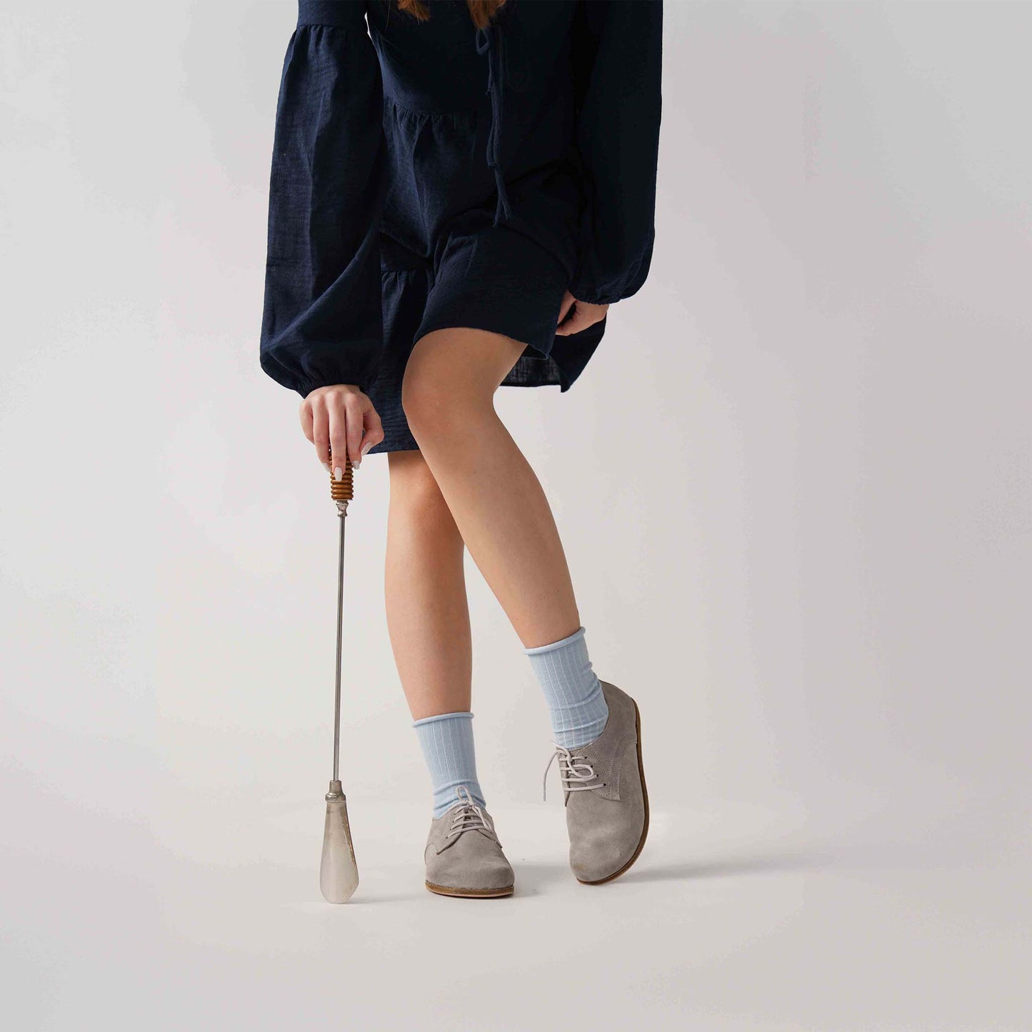 Gray suede Locris Leather Barefoot Women Oxfords paired with blue socks and a navy dress, showcasing a chic and versatile style.