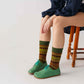 Model sitting with green Locris Leather Barefoot Women Oxfords paired with colorful patterned socks, highlighting style and natural fit. Ideal for stylish comfort.