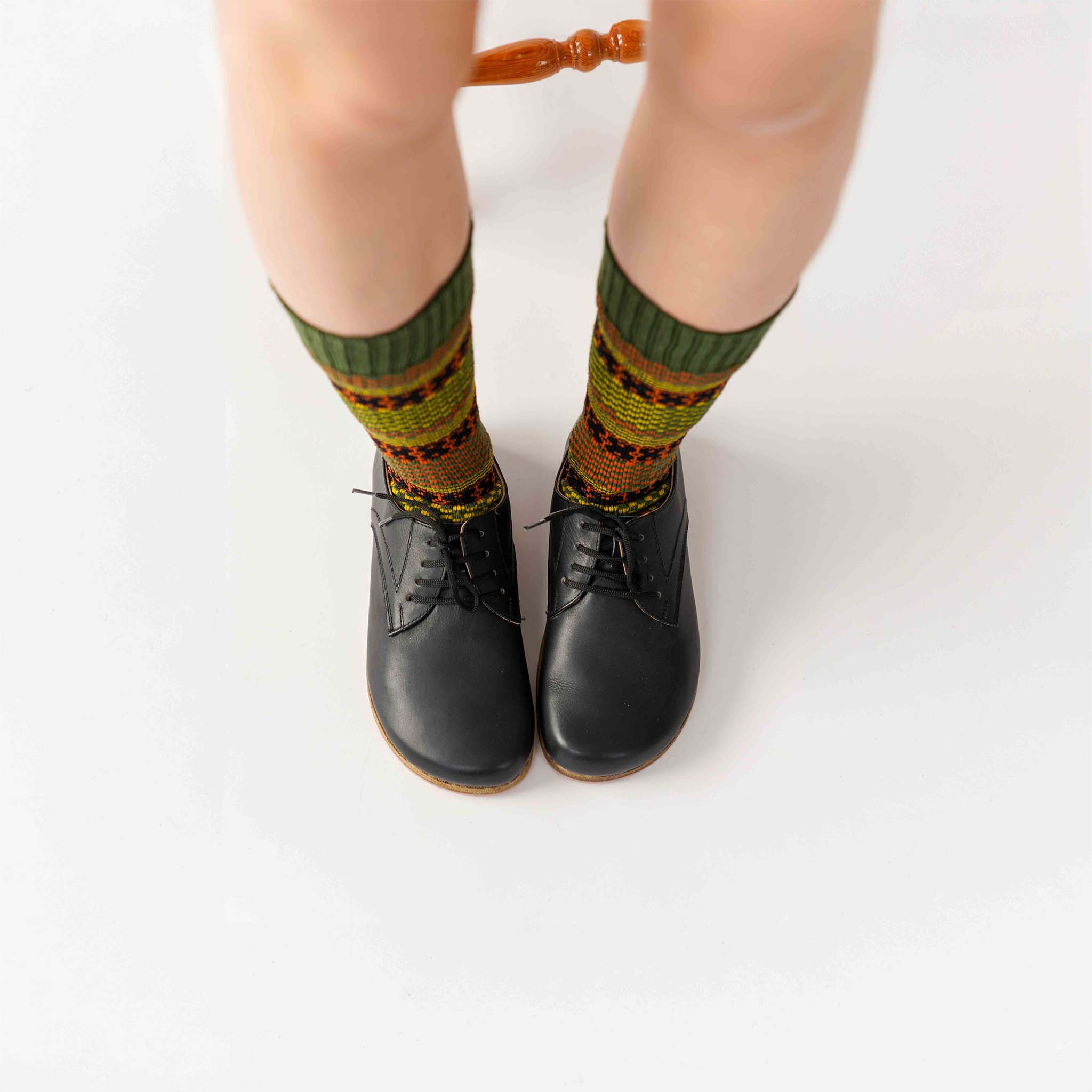 Top-down view of black Locris Leather Barefoot Women Oxfords worn with colorful patterned socks, highlighting the unique and stylish combination.