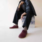 Model sitting with Locris Leather Barefoot Men's Oxfords in burgundy, paired with black pants for a sophisticated look.