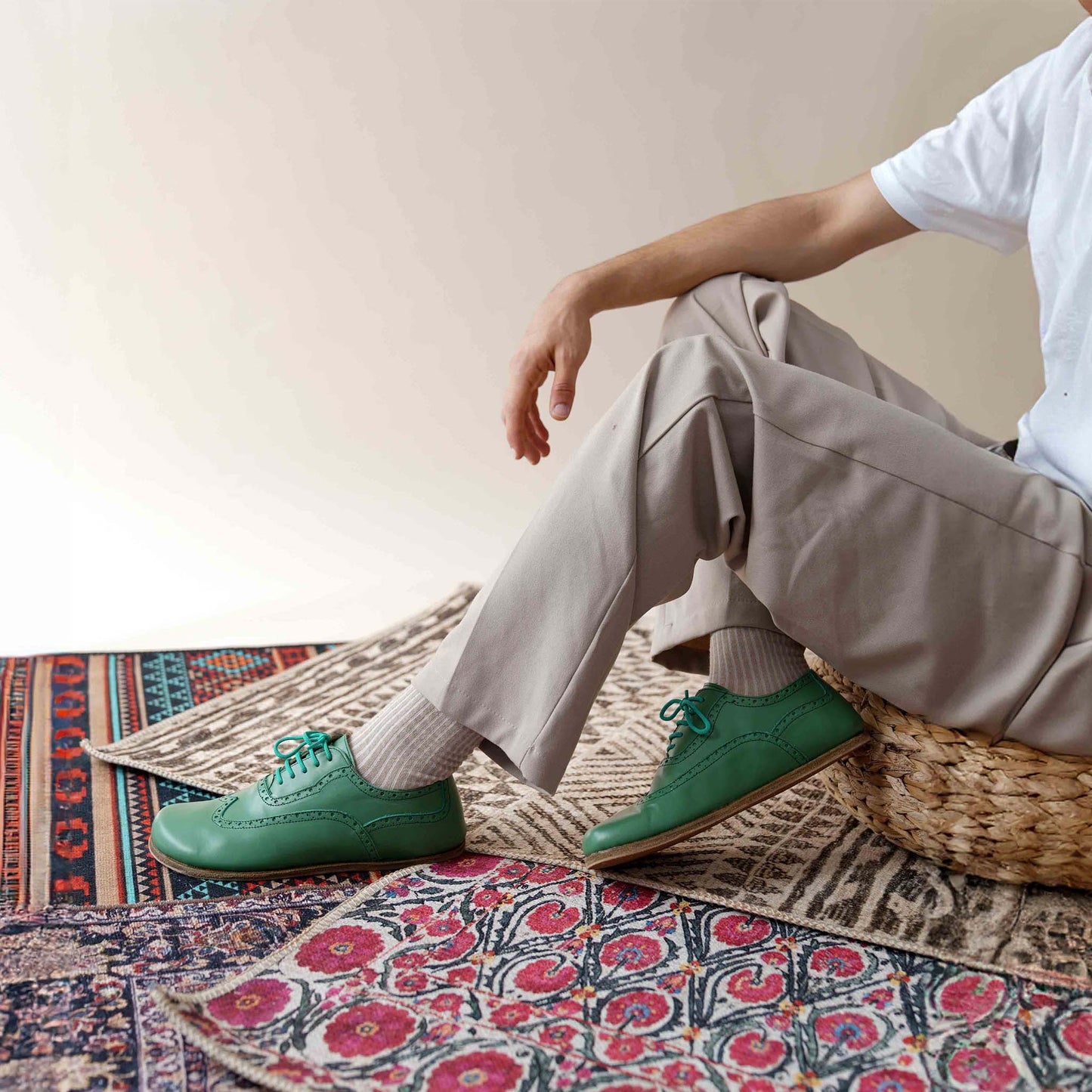 Man posing in green Doris Leather Barefoot Oxfords, emphasizing their classic brogue design and fit.