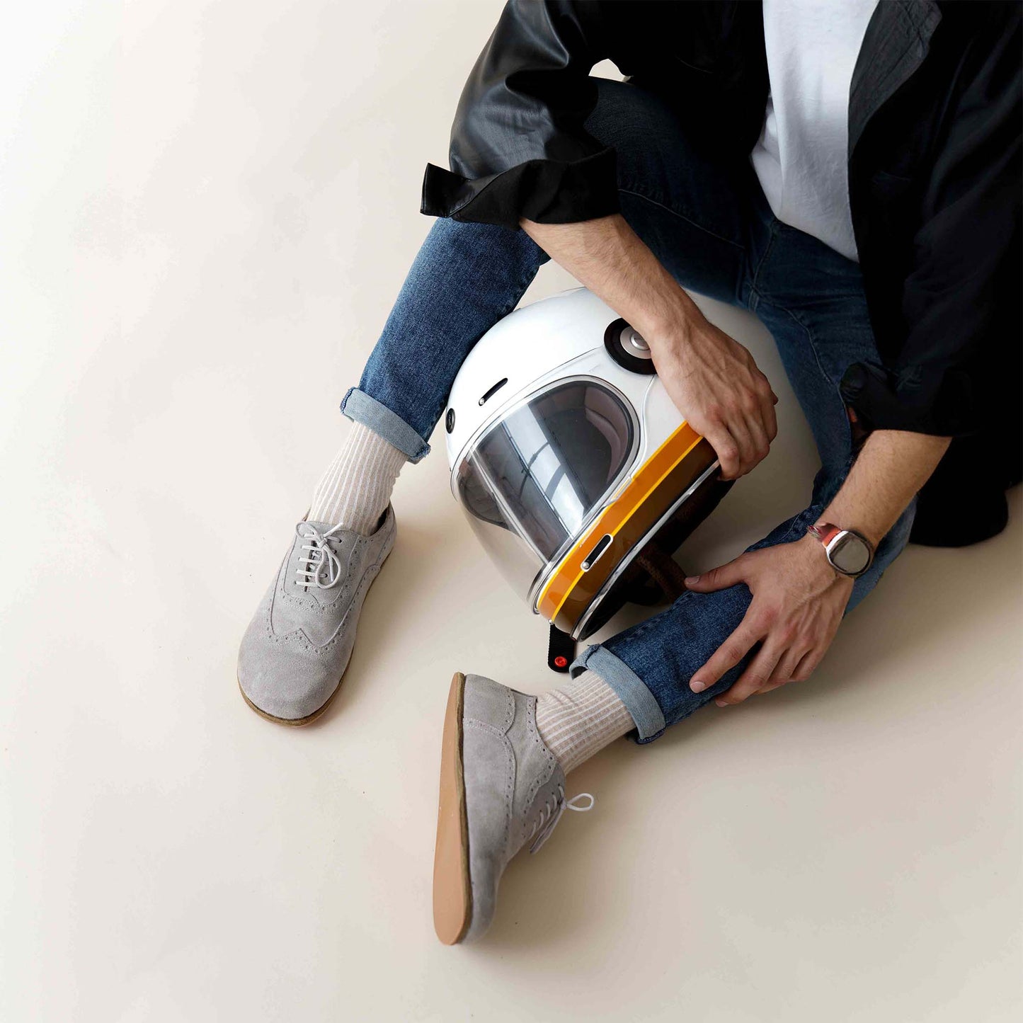Man wearing gray suede barefoot Oxfords paired with jeans and a white helmet – casual and trendy.