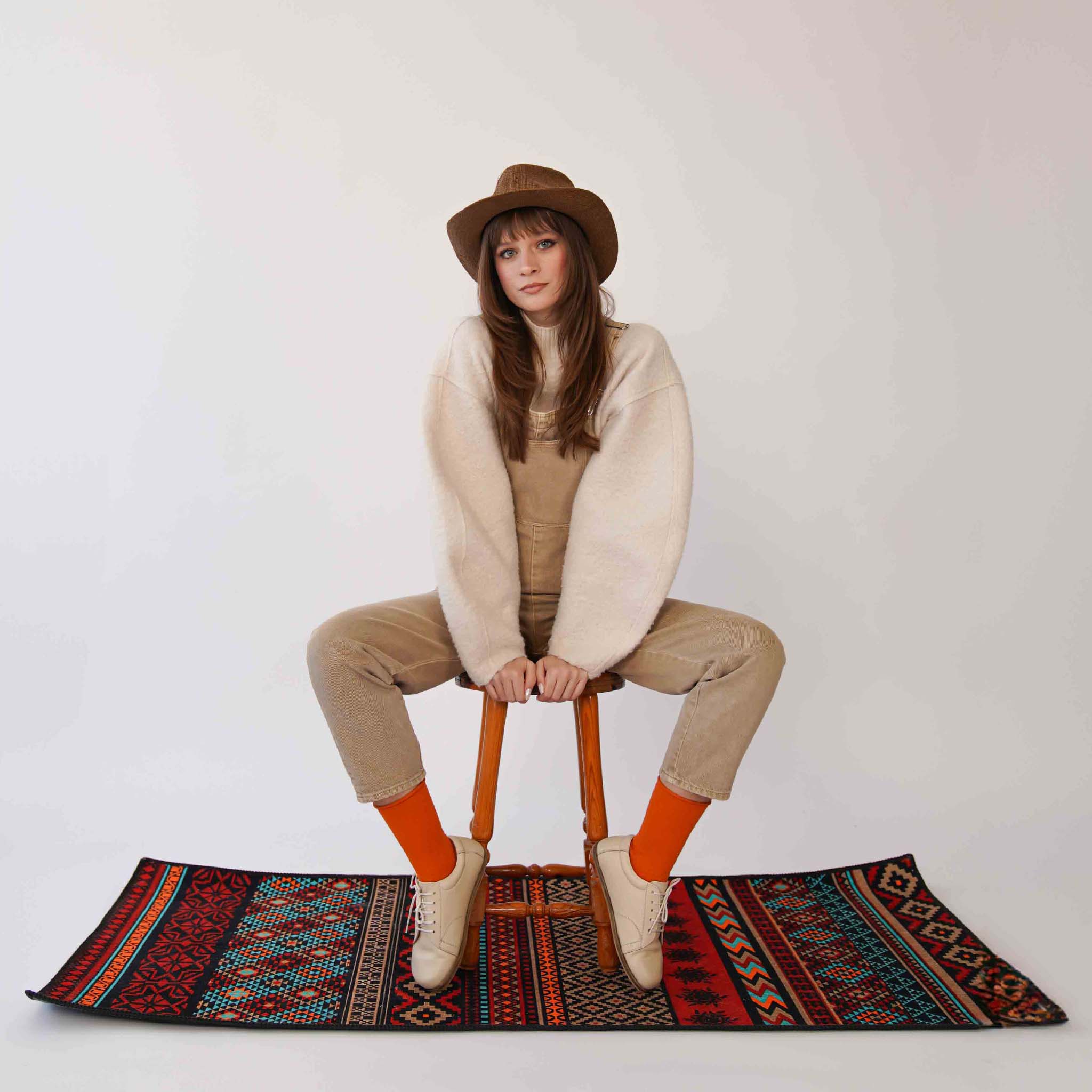 Model in beige leather barefoot women's sneakers, paired with bright orange socks, reflecting a chic and modern lifestyle.