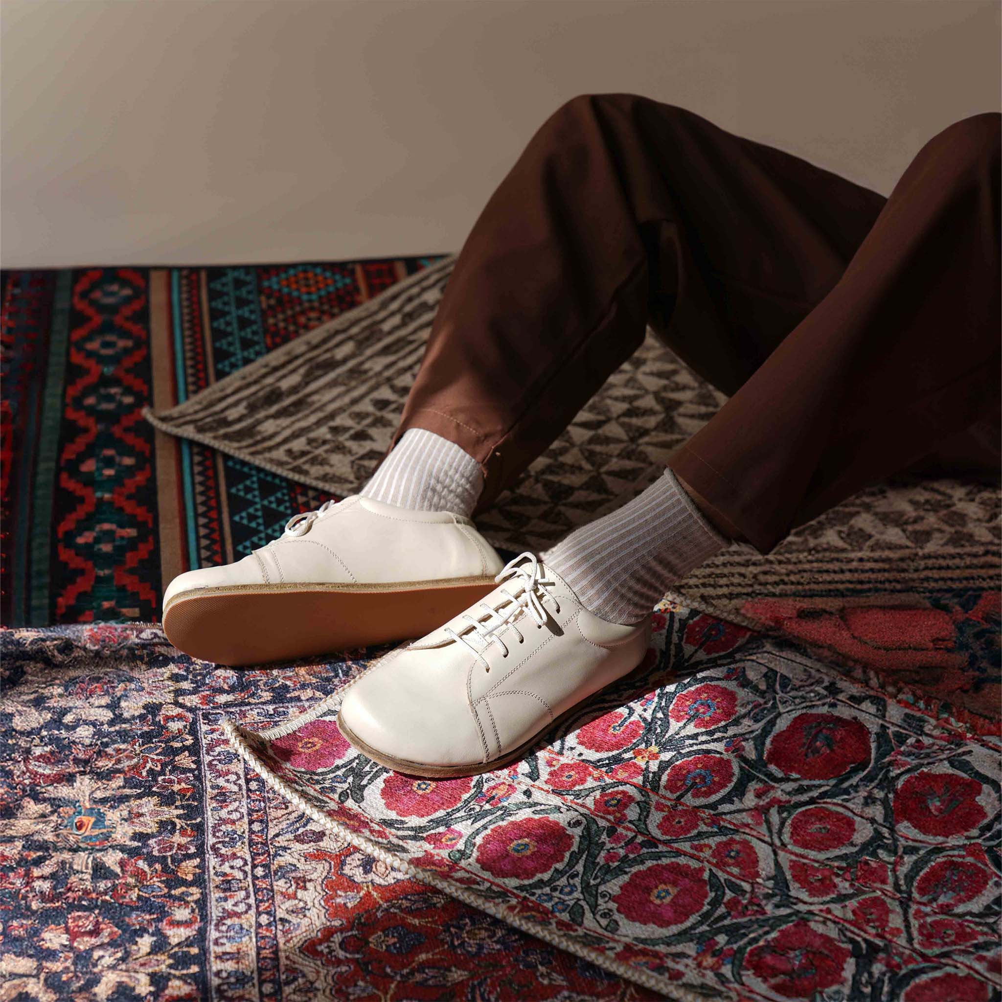 Relaxed shot of Lydia Leather Barefoot Men's Sneakers in beige, emphasizing the natural fit and classic design for a comfortable lifestyle.