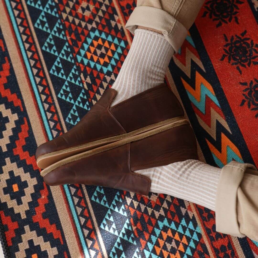 Brown barefoot loafers on a colorful Turkish traditional carpet.